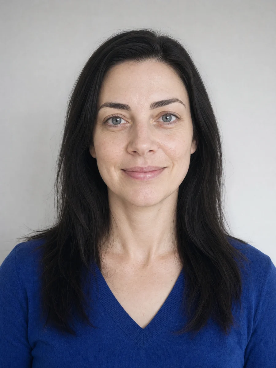 A woman with light skin, dark ash-brown hair, gray-blue eyes and a sapphire-blue top.