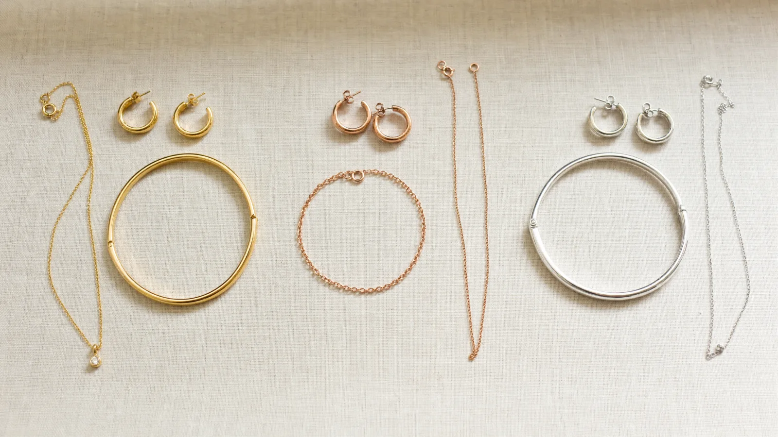 Gold, rose gold and silver earrings, bracelets and chains shown side by side.
