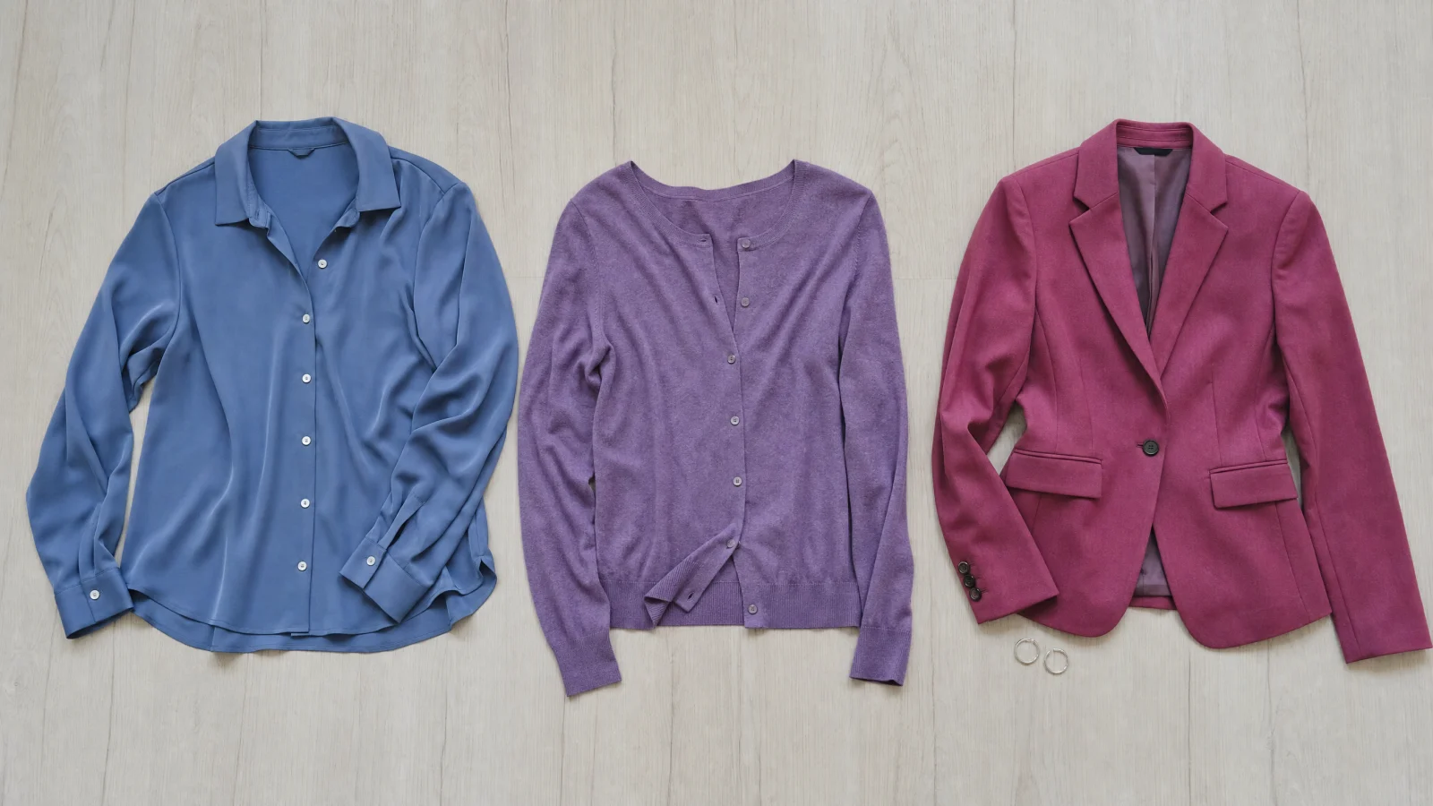 Three wearable garments laid side by side in French Blue, Amethyst, Raspberry Rose.