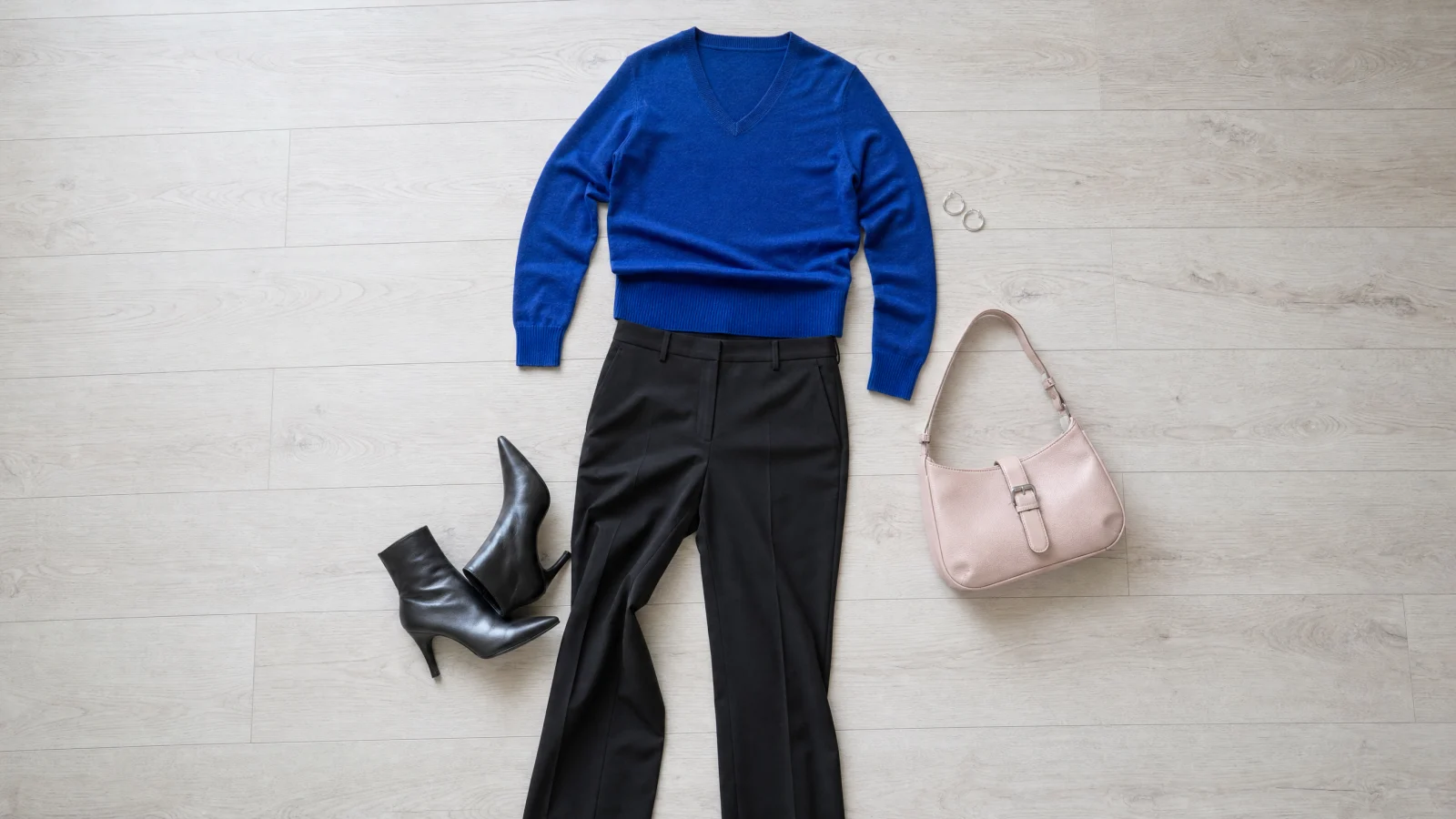 A sapphire V-neck knit with black tailored trousers, leather ankle boots, an icy pink shoulder bag and silver hoops.